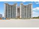 Stunning exterior view of a high-rise condo building on a sandy beach under a clear blue sky at 201 Ocean Blvd. S # 1505, North Myrtle Beach, SC 29582