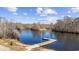 A charming dock extends into the river, framed by trees and grassy banks, on a sunny day with scattered clouds at 3565 Steamer Trace Rd., Conway, SC 29527
