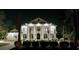 Nighttime view of an elegant home showcasing classic architecture, illuminated columns, and meticulously landscaped grounds at 4110 Gray Heron Dr., North Myrtle Beach, SC 29582