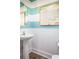 Stylish half-bathroom with pedestal sink, decorative mirror, wainscoting, and turquoise accent wall at 437 Falling Leaf Loop, Myrtle Beach, SC 29588