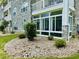 Landscaping rocks surround a condo building with a sunroom and beautiful white accents at 4783 Wild Iris Dr. # 101, Myrtle Beach, SC 29577