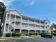 Exterior shot of multi-story condominium featuring white balconies and ample parking at 4783 Wild Iris Dr. # 101, Myrtle Beach, SC 29577