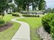 Winding sidewalk leading to the community pool and amenity area, surrounded by green grass and landscaping at 4783 Wild Iris Dr. # 101, Myrtle Beach, SC 29577