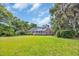 Spacious backyard with lush green grass, mature trees, and a brick house with a screened porch at 520 Chapman Loop, Pawleys Island, SC 29585