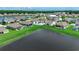 Aerial view showcases a neighborhood with numerous houses, some featuring screened porches and pools, bordering a serene lake at 5406 Longhorn Dr., Myrtle Beach, SC 29588