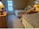Cozy bedroom with two beds, floral bedding, a dresser with a lamp, and a door to the balcony at 6103 N Ocean Blvd. # C-6, North Myrtle Beach, SC 29582
