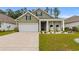 Inviting home with green siding, a white garage door, and a cozy front porch with seating at 736 Flowering Branch Ave., Little River, SC 29566
