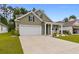 Inviting home with a two car garage, covered front porch, and green grass at 736 Flowering Branch Ave., Little River, SC 29566