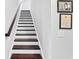 A staircase with wood treads, white risers, a wooden handrail, and framed art at 802 Devon Estate Ave., Myrtle Beach, SC 29588