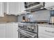 Stainless steel gas range with microwave and backsplash in kitchen with white cabinets and countertop at 8185 Sandlapper Way, Myrtle Beach, SC 29572