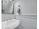 Elegant powder room with a pedestal sink, decorative mirror, and soft blue wainscoting for a classic touch at 8185 Sandlapper Way, Myrtle Beach, SC 29572
