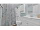 Bright bathroom featuring a tub with a patterned shower curtain and a spacious, modern vanity at 9501 Shore Dr. # A-211, Myrtle Beach, SC 29572