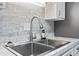 Close up on stainless steel kitchen sink with gray backsplash and white cabinets at 10301 N Kings Hwy. # 10-4, Myrtle Beach, SC 29572