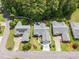 Aerial view of three well-manicured homes in a tree-lined neighborhood with manicured lawns at 1105 Lampwick Ln., Murrells Inlet, SC 29576