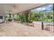 View of a covered patio with stone flooring and a built-in grill overlooking a swimming pool and lush landscaping at 115 Ford Ave, Mullins, SC 29574