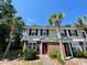 Charming townhouse with palm trees, a red front door, and well-maintained landscaping at 1432 Highway 544 # B2, Conway, SC 29526