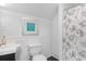 A bright bathroom features clean white fixtures, tiled wall, and decorative seashell shower curtain at 1516 James Island Ave., North Myrtle Beach, SC 29582