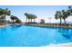 Large, outdoor pool area surrounded by tropical palm trees and lounge chairs at 2710 N Ocean Blvd. # 402, Myrtle Beach, SC 29577