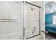 Bathroom featuring a shower and tub combination with glass doors and white tiled walls plus view to bedroom at 4501 S Ocean Blvd., North Myrtle Beach, SC 29582
