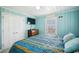 This coastal-themed bedroom features bright turquoise walls, a TV, closet, and a large window at 4501 S Ocean Blvd., North Myrtle Beach, SC 29582