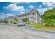 Exterior shot of a multi-story building with a parking lot, landscaping, and blue sky at 4683 Wild Iris Dr. # 104, Myrtle Beach, SC 29577