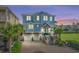 Two-story home at dusk featuring a meticulous brick driveway, two-car garage, and beautiful landscaping, including mature palm trees at 4832 Williams Island Dr., Little River, SC 29566
