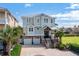 Stunning two-story home featuring a meticulous brick driveway, two-car garage, and beautiful landscaping, including mature palm trees at 4832 Williams Island Dr., Little River, SC 29566