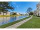 Scenic view of condo buildings overlooking a tranquil pond, framed by green grass and a paved walkway at 4895 Luster Leaf Circle # 304, Myrtle Beach, SC 29577