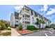 Three-story condo building featuring private balconies and well-maintained landscaping with trees and shrubs at 5001 N Ocean Blvd. # 1F, North Myrtle Beach, SC 29582