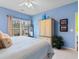 Comfortable bedroom with light blue walls, neutral carpet, wardrobe and a large window offering natural light at 5840 Longwood Dr. # 303, Murrells Inlet, SC 29576