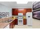 Functional kitchen with wood cabinets, stainless steel sink, white appliances, and adjacent breakfast bar at 5840 Longwood Dr. # 303, Murrells Inlet, SC 29576