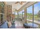 Relaxing sunroom with brick accent wall, comfortable seating, ceiling fans, and scenic backyard views through expansive windows at 967 Henry James Dr., Myrtle Beach, SC 29579