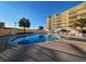 Exterior of condo complex featuring a pool with sun loungers and palm trees against a clear blue sky at 125 South Dunes Dr., Pawleys Island, SC 29585