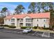 Two-story condo featuring covered porches, a red roof, manicured landscaping, and convenient parking spaces at 193 Charter Dr. # E7, Longs, SC 29568