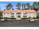 Two-story condo with covered porches, a red roof, mature landscaping, and parking spaces at 193 Charter Dr. # E7, Longs, SC 29568