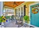 Inviting front porch with rocking chairs, ceiling fan, and a colorful wreath on the teal front door at 305 Goddard Ln., Murrells Inlet, SC 29576