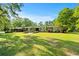 Well-manicured front yard with lush green grass and mature trees surrounding a brick home at 3173 Long Avenue Ext., Conway, SC 29526
