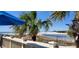 Serene beach view from a patio with palm trees, the American flag, and a glimpse of the shoreline and nearby buildings at 415 Ocean Creek Dr. # 2161, Myrtle Beach, SC 29572
