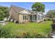 Brick home showcasing a well-kept lawn, sunroom, and vibrant flower bushes against a green backdrop at 44 Hamby Dr., Pawleys Island, SC 29585