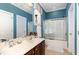 Bright bathroom with a white vanity, tile flooring, and glass enclosed tub at 4608 Grovecrest Circle, North Myrtle Beach, SC 29582
