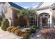 Home's inviting entryway features a decorative front door, a palm tree, and manicured landscaping at 4608 Grovecrest Circle, North Myrtle Beach, SC 29582
