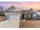 Charming single-story home featuring a two-car garage, brick accents, and a covered front porch under a colorful sunset at 610 Lightwood Dr., Conway, SC 29526