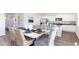 Bright dining room featuring a white table set for six with wicker chairs and a kitchen with stainless steel appliances at 738 Chazen Way, Longs, SC 29568