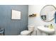 Stylish powder room with textured wallpaper, round mirror, and pedestal sink at 738 Chazen Way, Longs, SC 29568