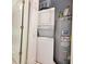 Compact utility room featuring a stacked washer/dryer, and hot water heater behind louvered doors at 75-4 Weehawka Way # 4, Pawleys Island, SC 29585