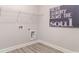 Modern laundry room with gray luxury vinyl plank flooring, crisp white walls, and upper shelving at 846 Ireland Dr., Longs, SC 29568