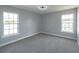 A cozy bedroom with soft carpeting, two large windows offering natural light, and neutral-toned walls at 1031 Snowberry Dr., Longs, SC 29568