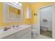 A pristine yellow bathroom has white cabinets and tile, and leads to a closet for convenient storage at 107 Waterway Crossing Ct., Little River, SC 29566
