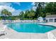 Community pool surrounded by lounge chairs and tables under a blue sky and surrounded by mature trees at 111 Rose Water Loop, Myrtle Beach, SC 29588