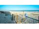 Scenic beach view with a line of wooden fences, beach grass, a bright blue garbage can, and a sign at 1207 South Ocean Blvd. # 51106, Myrtle Beach, SC 29577